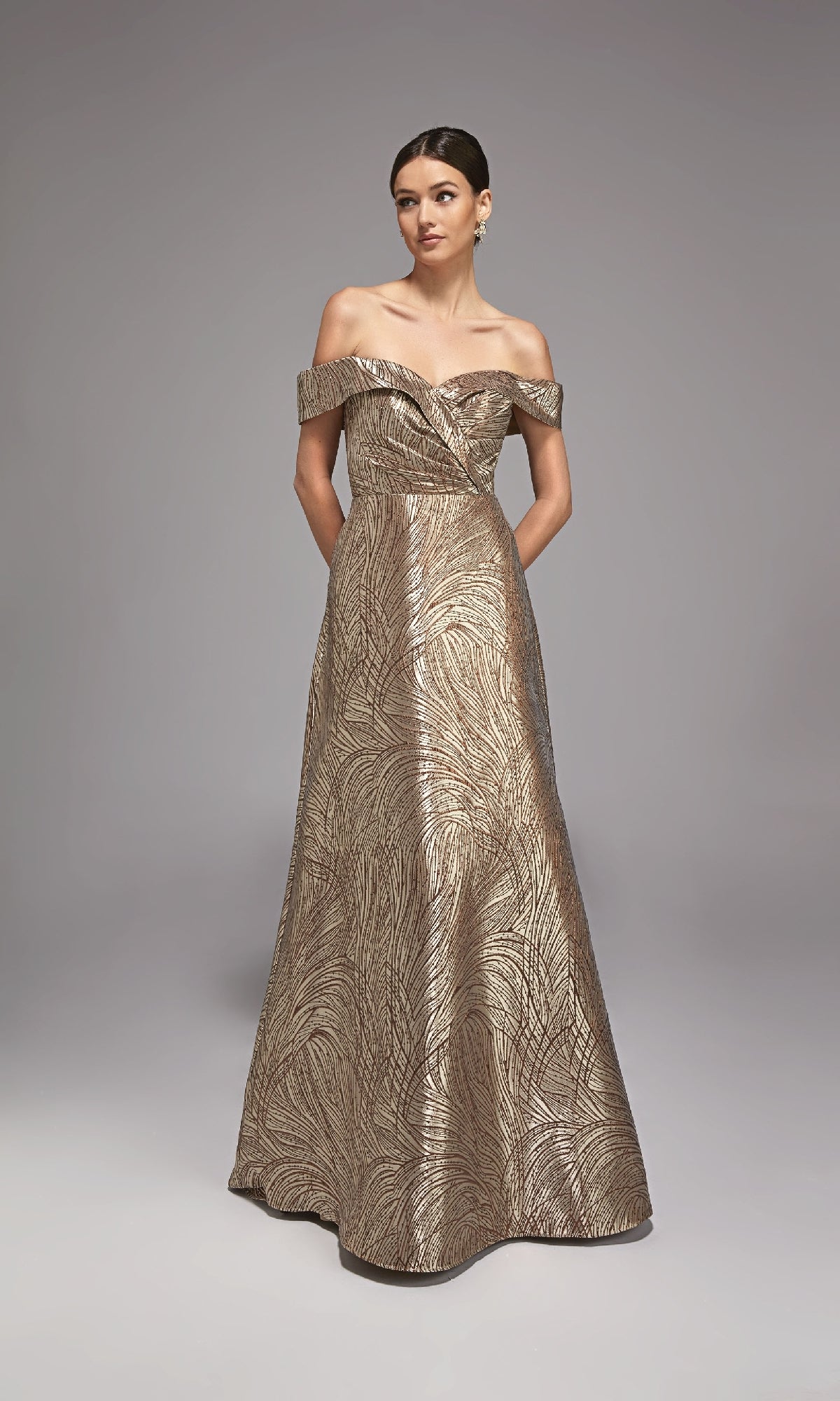 A woman poses against a plain background in the Alyce 27844 long formal dress, featuring metallic jacquard fabric, off-the-shoulder floor-length silhouette, and a delicate leaf pattern—an elegant choice for a mother-of-the-bride.